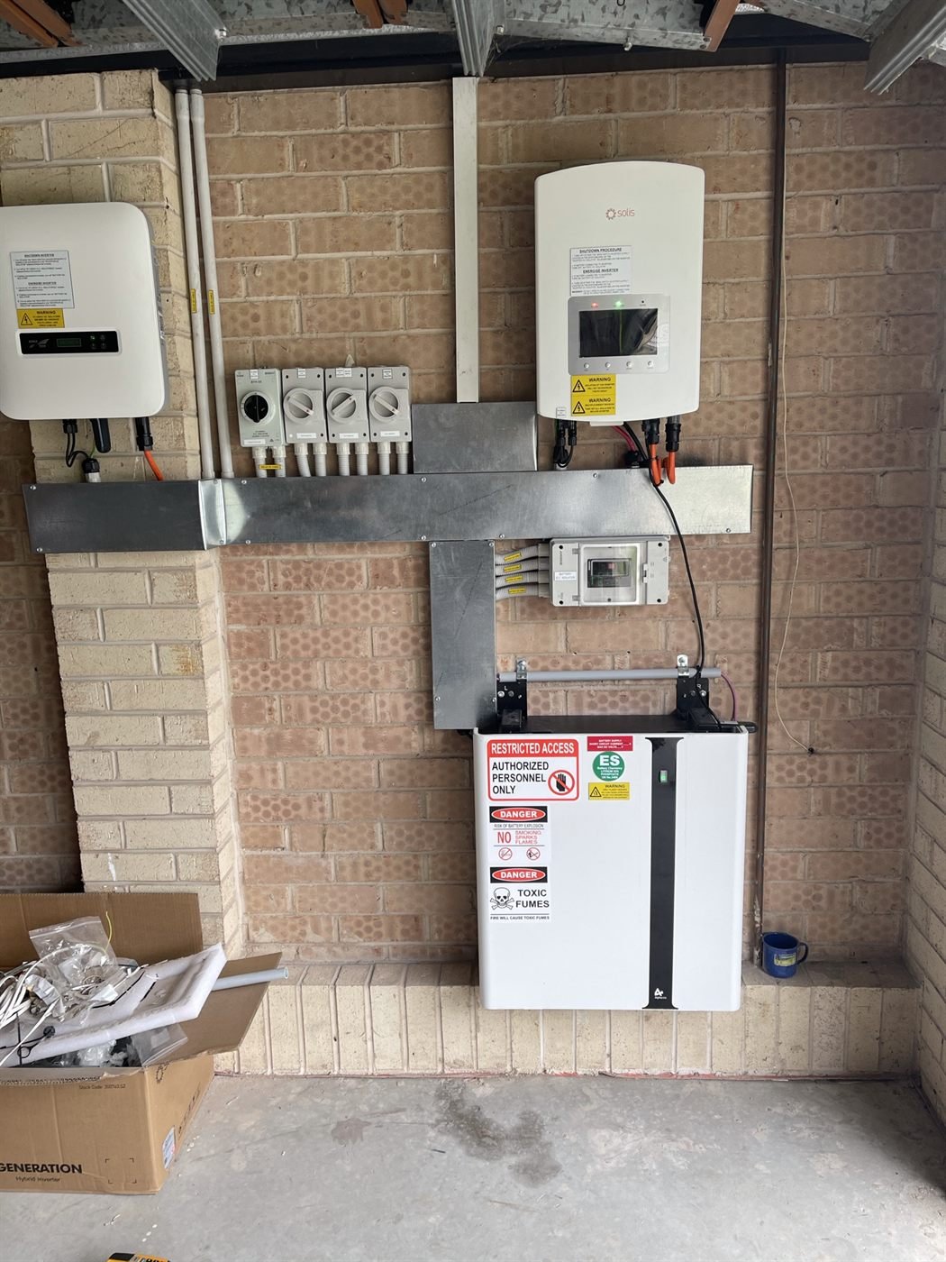 Wall-mounted battery and switchboard install in a brick garage