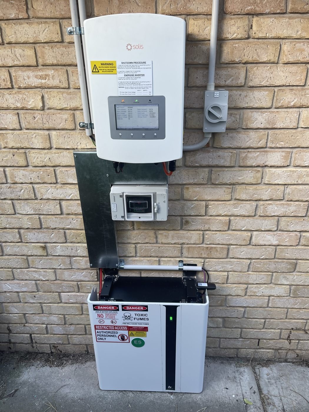 Solis hybrid inverter and battery on a brick wall